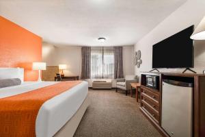 a hotel room with a bed and a flat screen tv at Howard Johnson by Wyndham Oacoma Hotel & Suites in Oacoma +27 photos