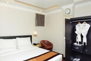 a hotel room with a bed and a chair and a clock at Hotel Bond in Yangon