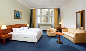 a hotel room with a bed and a couch and chair at Wyndham Garden Berlin Mitte in Berlin +75 photos