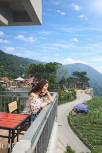 a woman sitting on a fence talking on a cell phone at Sun Villa Tam Đảo in Vĩnh Phúc