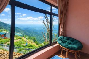 a room with a window with a green chair and a view at Sun Villa Tam Đảo in Vĩnh Phúc