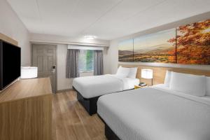 a hotel room with two beds and a flat screen tv at Days Inn by Wyndham Charleston WV in Charleston +18 photos