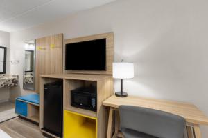 a room with a desk with a tv and a table with a chair at Days Inn by Wyndham Charleston WV in Charleston