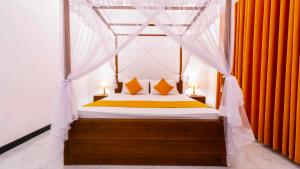 a bedroom with a canopy bed with orange curtains at Nimsara Lodge Sigiriya in Sigiriya
