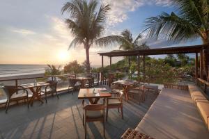 een restaurant met tafels en stoelen op een balkon met uitzicht op de oceaan bij Bali Niksoma Boutique Beach Resort in Legian