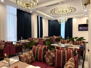 a dining room with tables and chairs and a chandelier at Surxondaryo Hotel Tashkent in Teshabayguzar