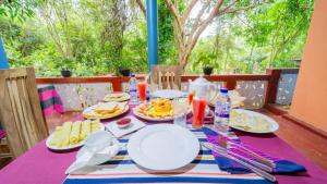 a table with plates of food and drinks on it at Nimsara Lodge Sigiriya in Sigiriya