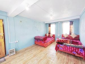 two beds in a room with blue walls and wooden floors at Betzer homestay in Cherrapunji