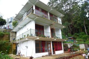 a white house with a balcony on top of it at Hilltop Panorama Ohiya in Ohiya