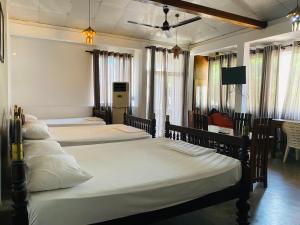 a bedroom with three beds and a flat screen tv at Amadio Beach Resort in Hikkaduwa