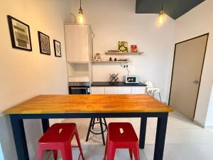 a kitchen with a wooden table and two red stools at R3troHouse3 4BR 14PAX Near188Tower, HTAA, In Town in Kuantan +15 photos