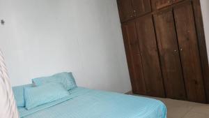 a bedroom with a bed with blue sheets and a wooden cabinet at Casita Puerto Maya in Puerto Aventuras