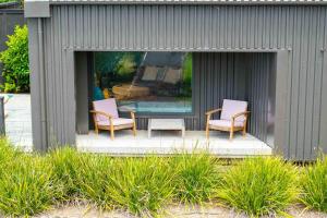 two chairs and a glass table on a patio at Up Above The Crescent in Waihi Beach
