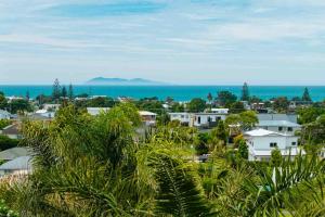 a city with houses and the ocean in the background at Up Above The Crescent in Waihi Beach