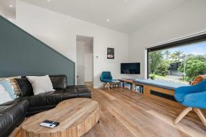 a living room with a couch and a table at Up Above The Crescent in Waihi Beach