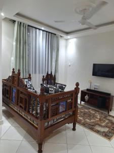 a bedroom with a large wooden bed and a flat screen tv at Serena10 in Mombasa