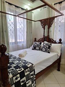 a bedroom with a canopy bed with pillows on it at Serena10 in Mombasa