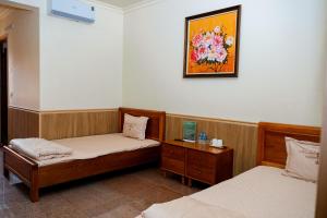 a bedroom with two beds and a picture on the wall at Bavieco - Nghỉ dưỡng, Dưỡng lão & Chữa bệnh theo Đông y in Ba Vì
