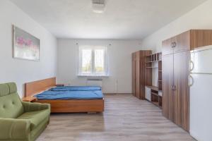 a bedroom with a bed and a couch and a refrigerator at Ubytovna Nika in Přerov