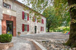 a brick building with red windows and a driveway at Logis Hotels - Au Colombier du Touron in Brax
