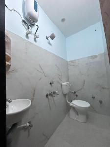 a white bathroom with a toilet and a sink at Shiva in Hāpur