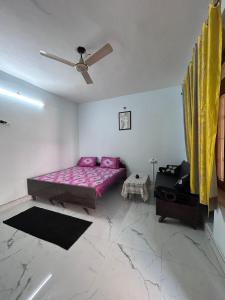 a bedroom with a purple bed and a ceiling fan at Shiva in Hāpur