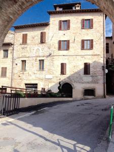 duży kamienny budynek z łukiem przed nim w obiekcie Spello House Dormio w mieście Spello
