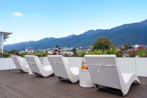 a row of chairs sitting on a balcony with mountains at 赛家花园酒店SAI JIA Garden HOTEL in Dali Ancient Town