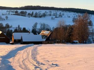 a barn in a snow covered field with a dirt road at Perfekte Auszeit im Erzgebirge in Sayda