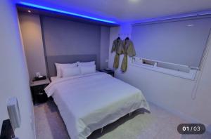 a bedroom with a white bed and a blue light at Hotel Social Stay in Pocheon