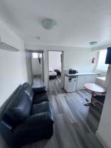 a living room with a black leather couch and a table at Citigate Motel Newcastle in Newcastle