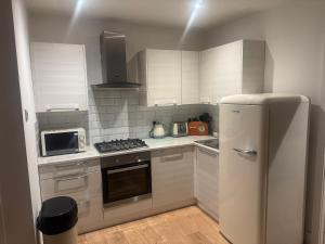 a kitchen with white cabinets and a refrigerator at A cozy self-contained bungalow in Margate