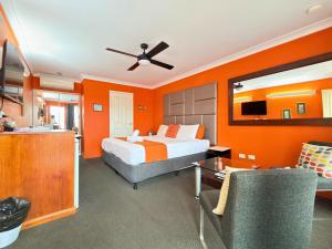 a bedroom with a bed and an orange wall at Aussie Rest Motel in Cessnock +36 photos