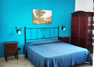 a bedroom with blue walls and a bed with a blue bedspread at Mariposa B&B in San Vito lo Capo