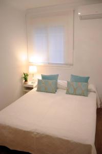 a bedroom with a large white bed with blue pillows at Reina Sofía Acogedor in Madrid
