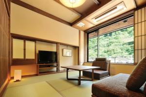 a living room with a table and a tv at Hinanoyado Chitose in Tokamachi