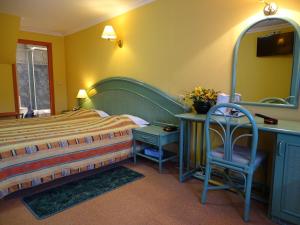 a bedroom with a bed and a chair and a mirror at Hotel Le Relais de Pommard in Francorchamps