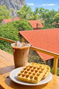 a cup of coffee and a plate of waffles and a drink at Trang An ViewPoint Homestay in Ninh Binh
