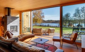 a living room with leather furniture and a large window at Villa SEE la vie in Rheinsberg