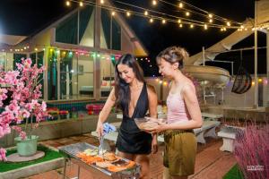 two women are preparing food on a grill at สายป่าน พลูวิลล่า in Cha Am