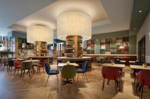 a restaurant with tables and chairs and a library at Hilton Garden Inn Rome Colosseum in Rome