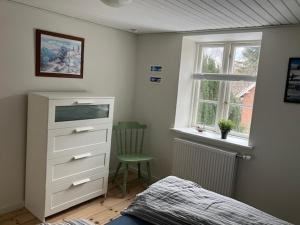 a bedroom with a bed and a dresser and a window at 1st floor 2 rooms with kitchenette in Store Heddinge