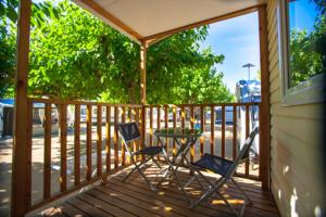 a patio with two chairs and a table on a deck at Camping el Pinar Platja in Santa Susanna