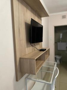 a television on a wooden wall with a glass shelf at Emangunini Guest house in Richards Bay