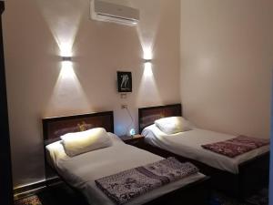 a room with two beds and a fan at Osama House Luxor in Al Qurnah