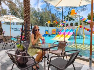 a woman sitting at a table in front of a pool at Firdaus Cafe& Hotel in Ban Bo So