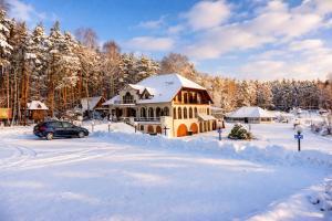 a house covered in snow with a car parked in front at Klimatyczne Domki - Całoroczne in Radomsko