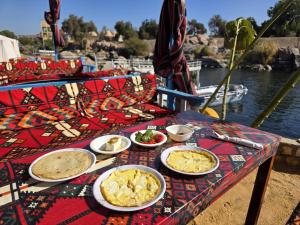 a table with plates of food on it next to the water at Hannag Island Guest house in Aswan
