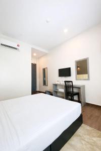 a bedroom with a large white bed and a desk at KARANG TIMUR Hotel in Kuantan