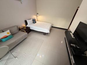 a room with a couch and a bed and a tv at 回家浪 in Hengchun South Gate